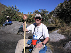 Hiker with a stick sitting on a boulder